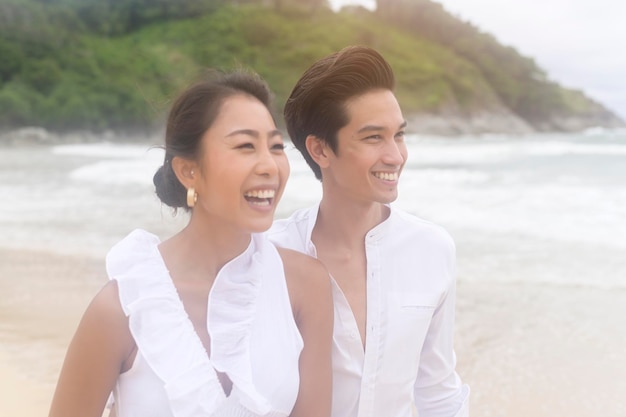 Heureux jeune couple vêtu d'une robe blanche sur la plage