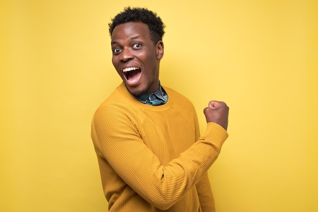 Photo heureux jeune étudiant afro-américain réussi montrant le poing