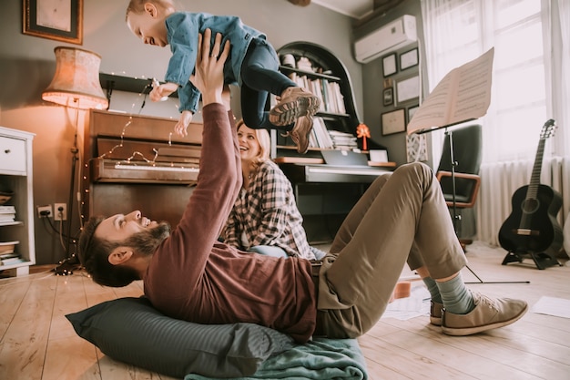 Heureux jeune famille jouant sur le sol dans la chambre