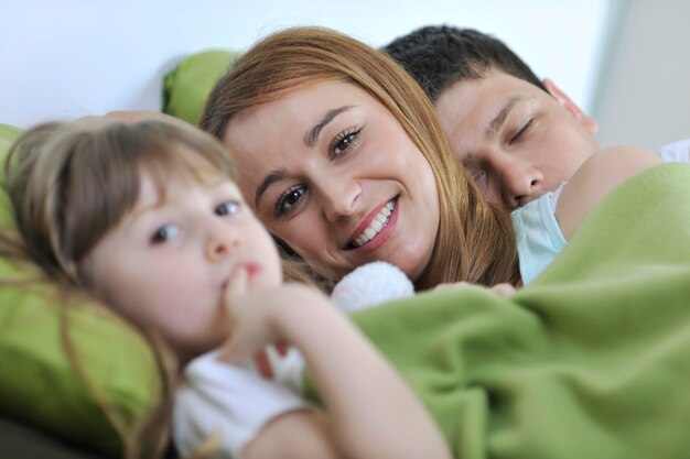 heureux jeune famille à la maison se détendre au lit