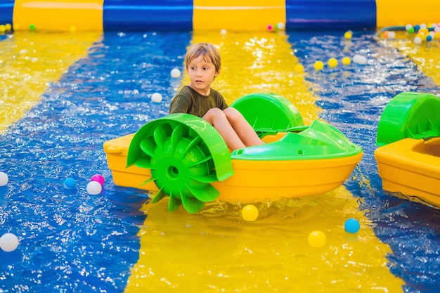 Heureux jeune garçon sur le bateau appréciant de jouer sur le parc d'attractions