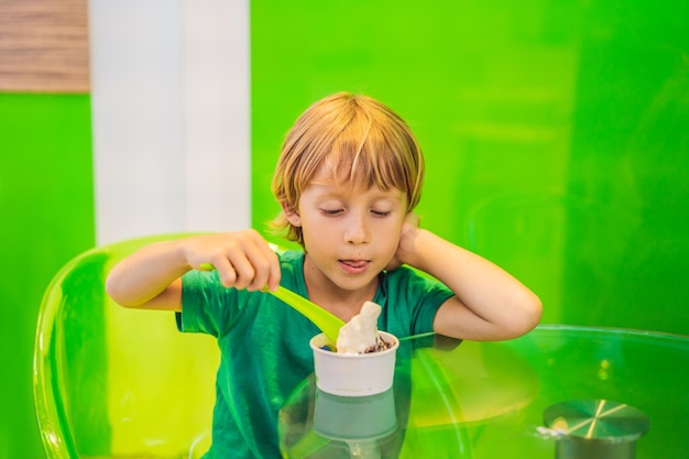 Heureux jeune garçon mangeant une savoureuse crème glacée ou un yaourt glacé