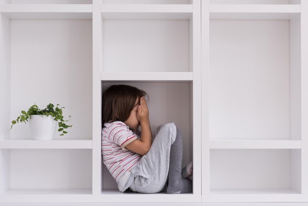 heureux jeune garçon s'amusant tout en posant sur une étagère dans une nouvelle maison moderne