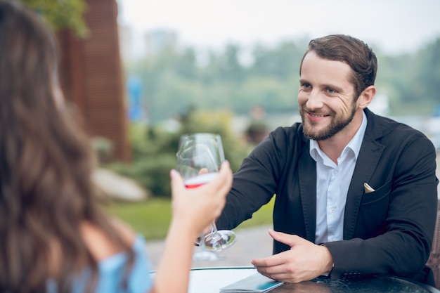 Heureux jeune homme adulte en chemise blanche et costume discutant avec une femme à la date au café d'été