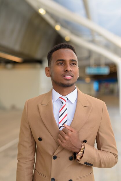 Heureux jeune homme d'affaires africain beau penser à la passerelle