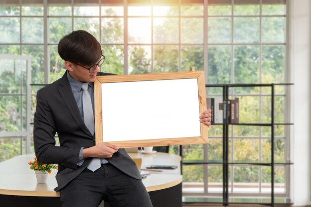 Heureux jeune homme d'affaires asiatique tenant un tableau blanc vide