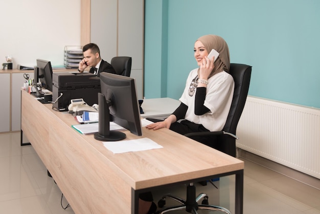Heureux jeune homme d'affaires et femme musulmane travaillent dans un bureau moderne sur ordinateur