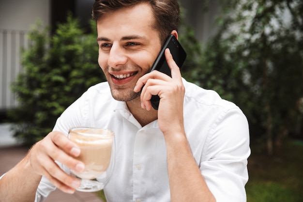 Heureux jeune homme d'affaires habillé en chemise, boire du café