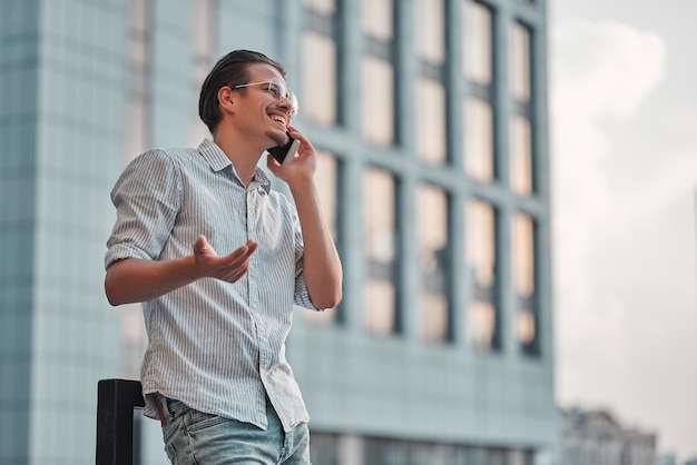 Heureux jeune homme d'affaires parlant au téléphone portable près du centre d'affaires.