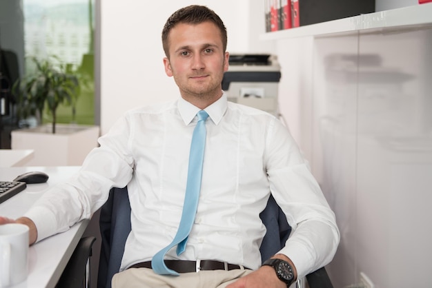 Heureux jeune homme d'affaires travaille dans un bureau moderne sur ordinateur