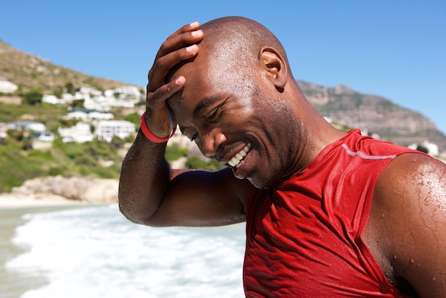 Heureux jeune homme africain à la plage après une baignade