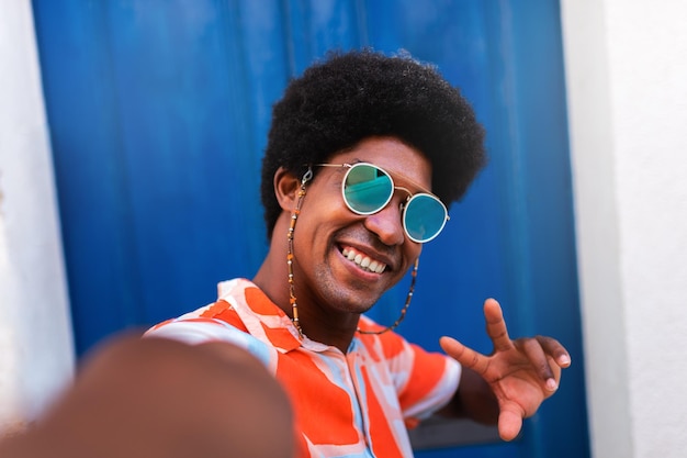 Heureux jeune homme afro-américain souriant prenant selfie dans un village méditerranéen côtier