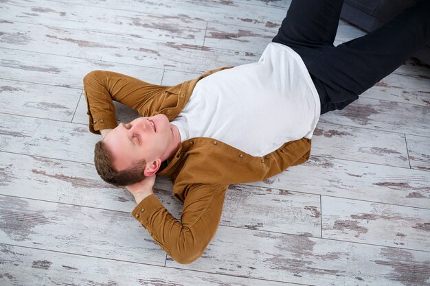 Heureux Jeune Homme Allongé Sur Le Sol Près Du Canapé Dans Le Salon Et Se Reposant