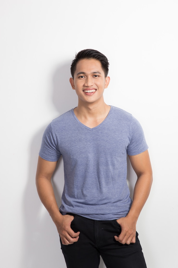 Photo heureux jeune homme asiatique posant les mains sur la taille, sourire à l'ac