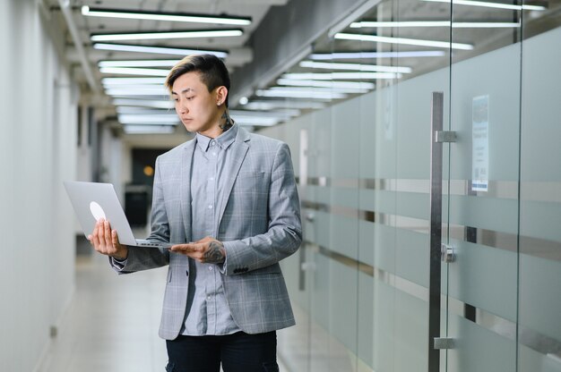 Heureux jeune homme assis dans un bureau moderne et regardant la caméra avec un sourire photo de haute qualité