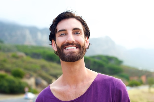 Heureux jeune homme à la barbe en souriant à l&#39;extérieur