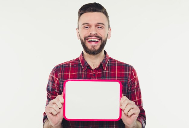 Heureux jeune homme barbu montrant et affichant une pancarte vide blanche prête pour votre texte ou produit ou annonce