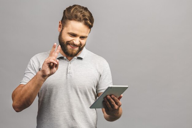 Heureux jeune homme barbu en position décontractée et à l'aide de tablette