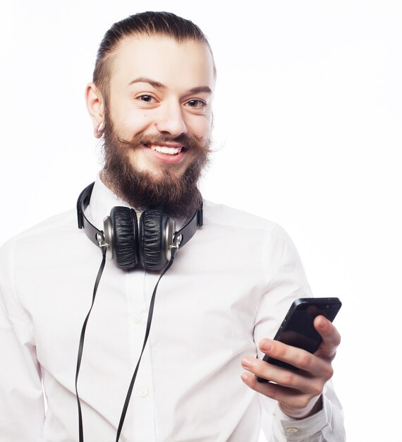 Heureux jeune homme barbu souriant avec mobile isolé sur fond blanc