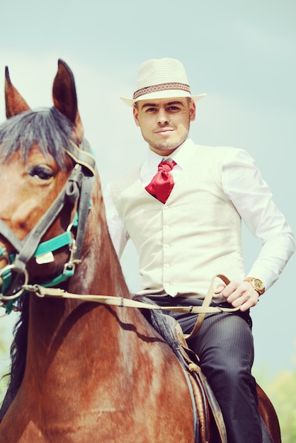 Heureux jeune homme sur la campagne avec cheval pour l&#39;équitation