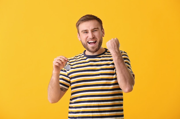 Heureux jeune homme avec une clé sur une surface de couleur