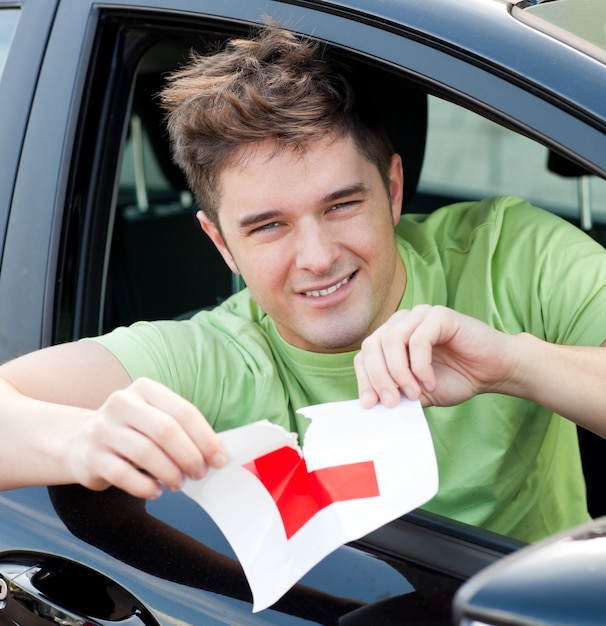 Heureux jeune homme conducteur déchirer son signe L