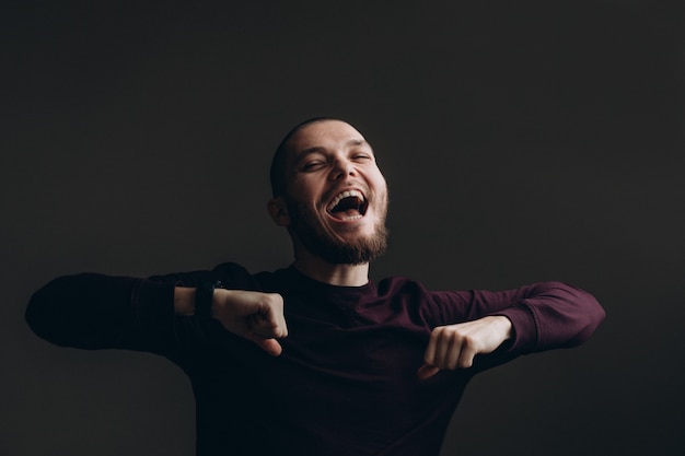 Heureux jeune homme dansant sur un espace gris. chauve avec une barbe