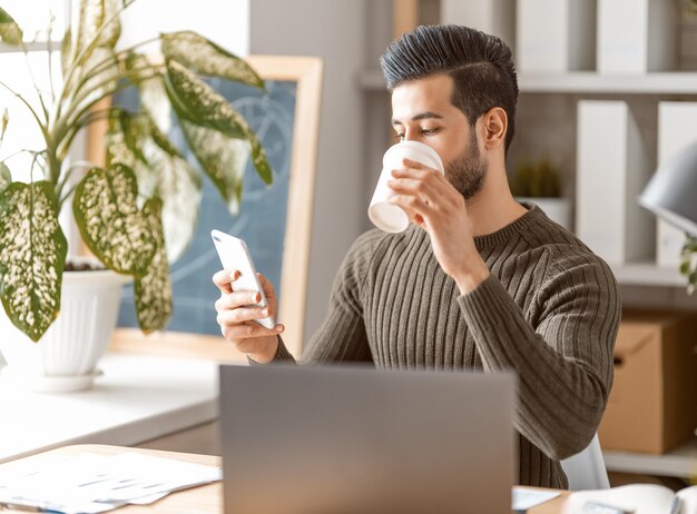 Heureux jeune homme décontracté travaillant sur un ordinateur portable à la maison.