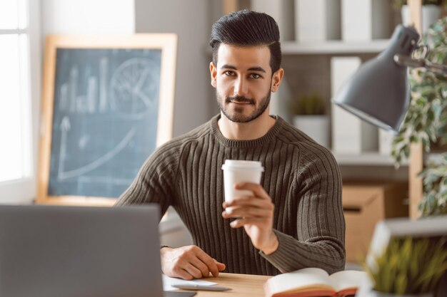 Heureux jeune homme décontracté travaillant sur un ordinateur portable à la maison.