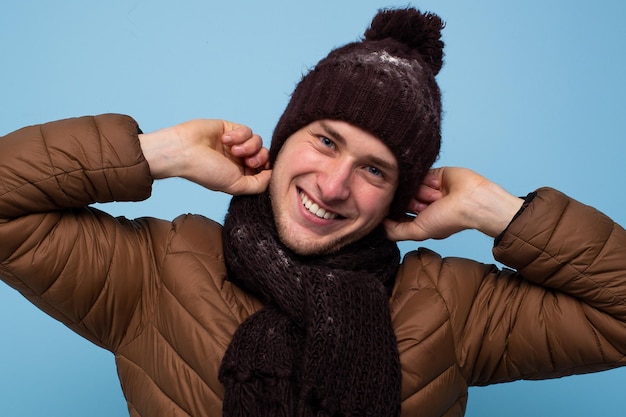 Heureux jeune homme en écharpe marron et chapeau d'hiver souriant