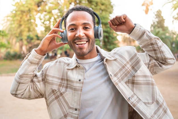 Photo heureux jeune homme écoutant de la musique et dansant avec des écouteurs dans la rue. espace pour le texte