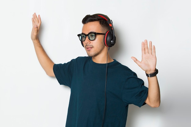 Heureux jeune homme écoutant de la musique dansant et s'amusant sur fond blanc