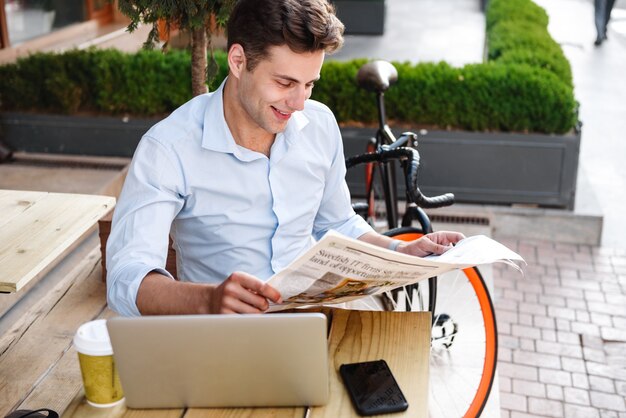 Heureux jeune homme élégant en chemise de lecture de journal