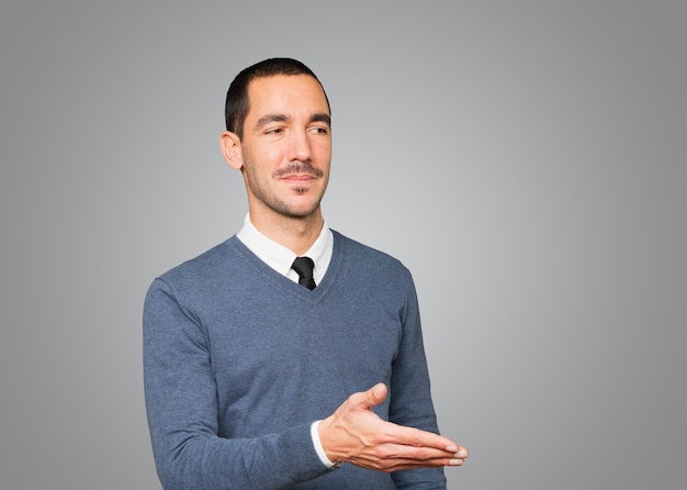 Heureux jeune homme faisant un geste de bienvenue avec sa main