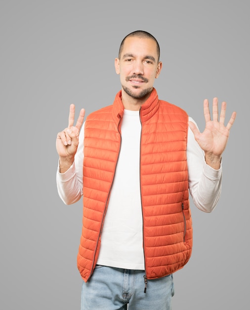 Heureux jeune homme faisant un geste numéro sept avec ses mains