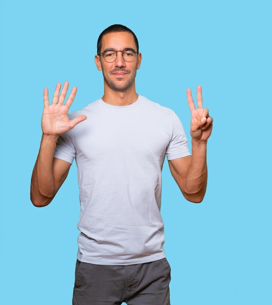 Heureux jeune homme faisant un geste numéro sept avec ses mains