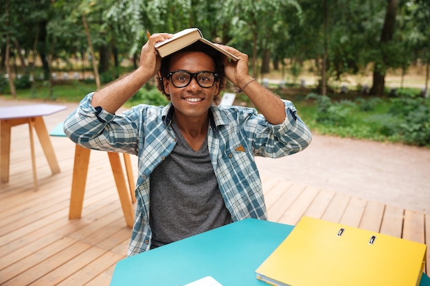 Heureux jeune homme à lunettes étudier et s'amuser dans un café en plein air