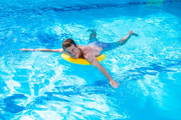Heureux jeune homme nage dans la piscine.