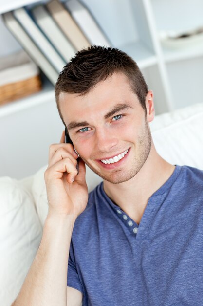 Heureux jeune homme parlant au téléphone en souriant à la caméra