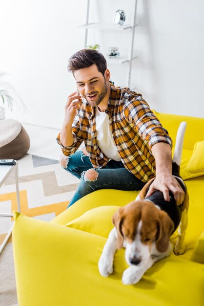 Heureux jeune homme parlant sur smartphone et regardant un chien