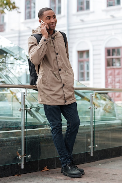 Photo heureux jeune homme parlant sur son téléphone dans la rue