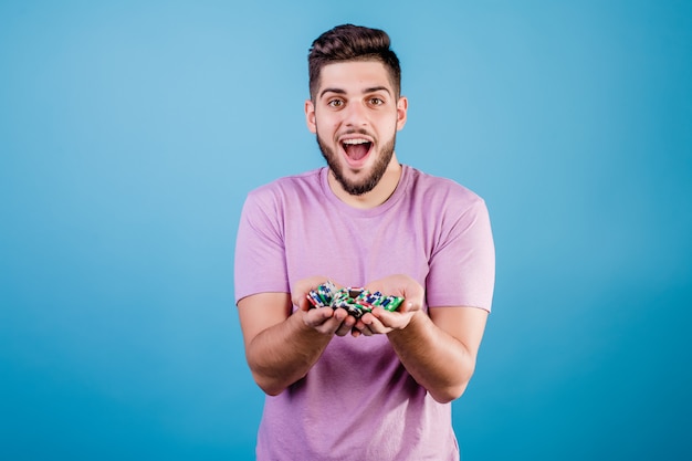 Heureux jeune homme avec une poignée de jetons de poker sur bleu