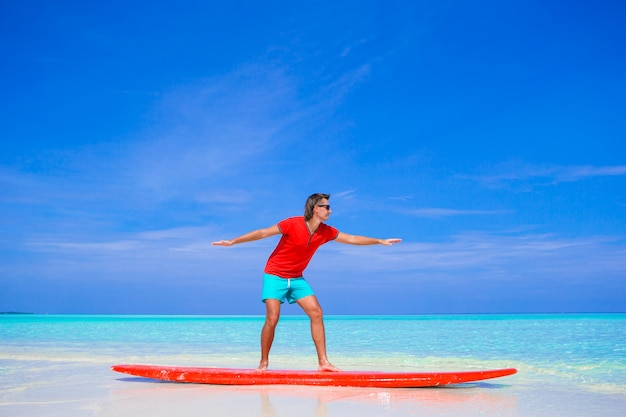 Heureux jeune homme pratiquant la position de surf sur la planche de surf