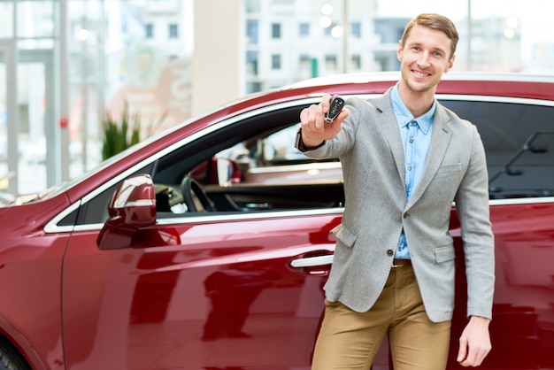 Heureux jeune homme présentant des clés de voiture