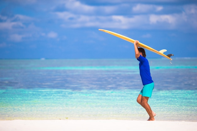 Heureux jeune homme surfer sur la côte tropicale
