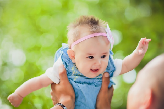 Heureux jeune homme tenant un bébé de 2 à 4 mois souriant sur fond de feuilles non mises au point