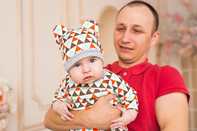 Heureux jeune homme tenant un bébé âgé de 4-5 mois souriant, isolé sur blanc