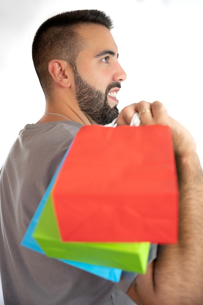 Heureux jeune homme tenant des sacs colorés sur son épaule concept shopping vente vendredi noir noël