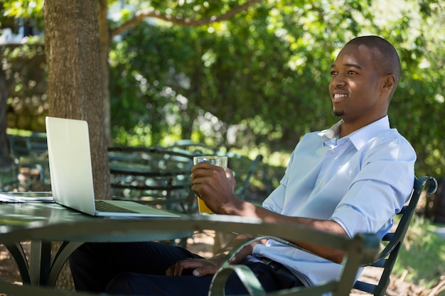 Heureux jeune homme tenant un verre de jus d'orange au restaurant