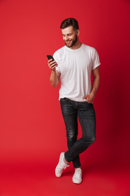 Heureux jeune homme utilisant un téléphone mobile.